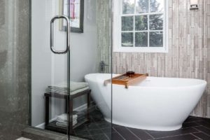 Elegant Transitional Style bathroom remodel. Features expanded shower, frameless glass, solid surface shower walls, walnut cabinetry and freestanding soaking tub. 