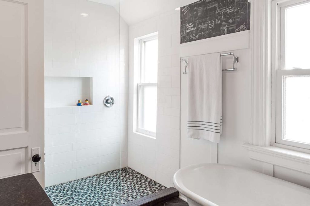 Victorian and modern fusion bathroom remodel design. Whimsy meets classic” style. Features subway tiles, trim to match existing millwork, and a wood-look ceramic floor set in a herringbone pattern. Vanity built from salvaged wood - modery and earthy counterpoint to traditional details. 