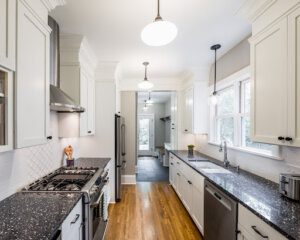 Galley Kitchen with dark countetops and white cabinetry