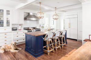 Luxury kitchen remodel and kitchen addition in colonial home. Traditional style, features island, butler's pantry, custom royal blue cabinetry and added family room. Dog in photo lying on floor next to island. Seating at island.