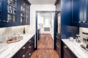 Luxury butler's kitchen remodel with marble countertops and dark blue cabinetry.