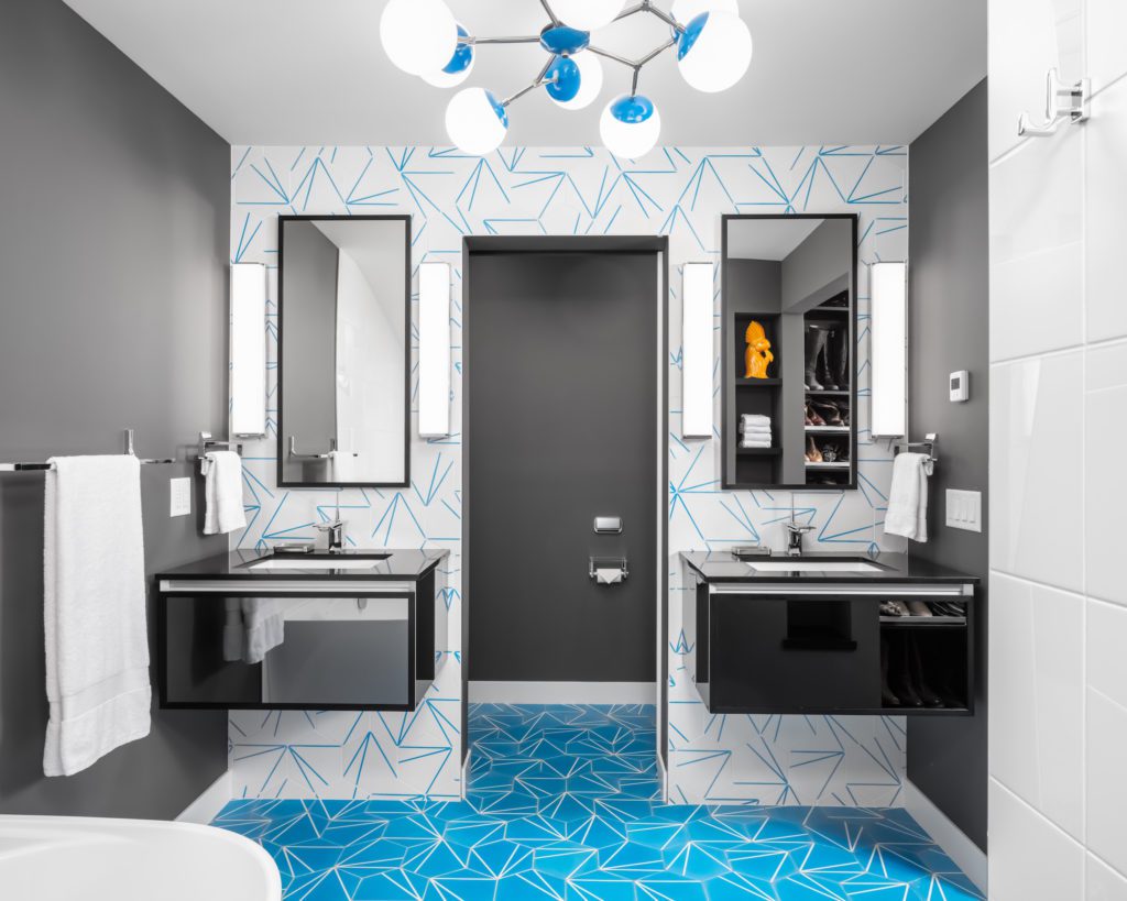 Mid-Century Moxie: A Master Bath Makeover. Modern bathroom remodel with cerulean blue floor tiles and geometric shower floor. Features polished chrome fixtures and double vanity.