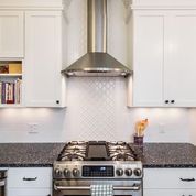 A kitchen with a granite countertop and white diamond backsplash