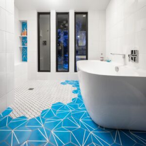 Bathroom with bright cerulean blue floor tiles and geometric shower floor; soaking tub with views to the lake and beyond