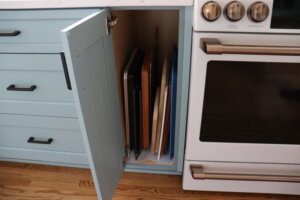 Taller kitchen drawer next to oven with cutting boards and cookie sheets.