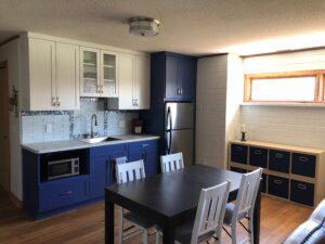 kitchen added to basement remodel. blue cabinets, hard wood floors, lots of windows, bright and sunny