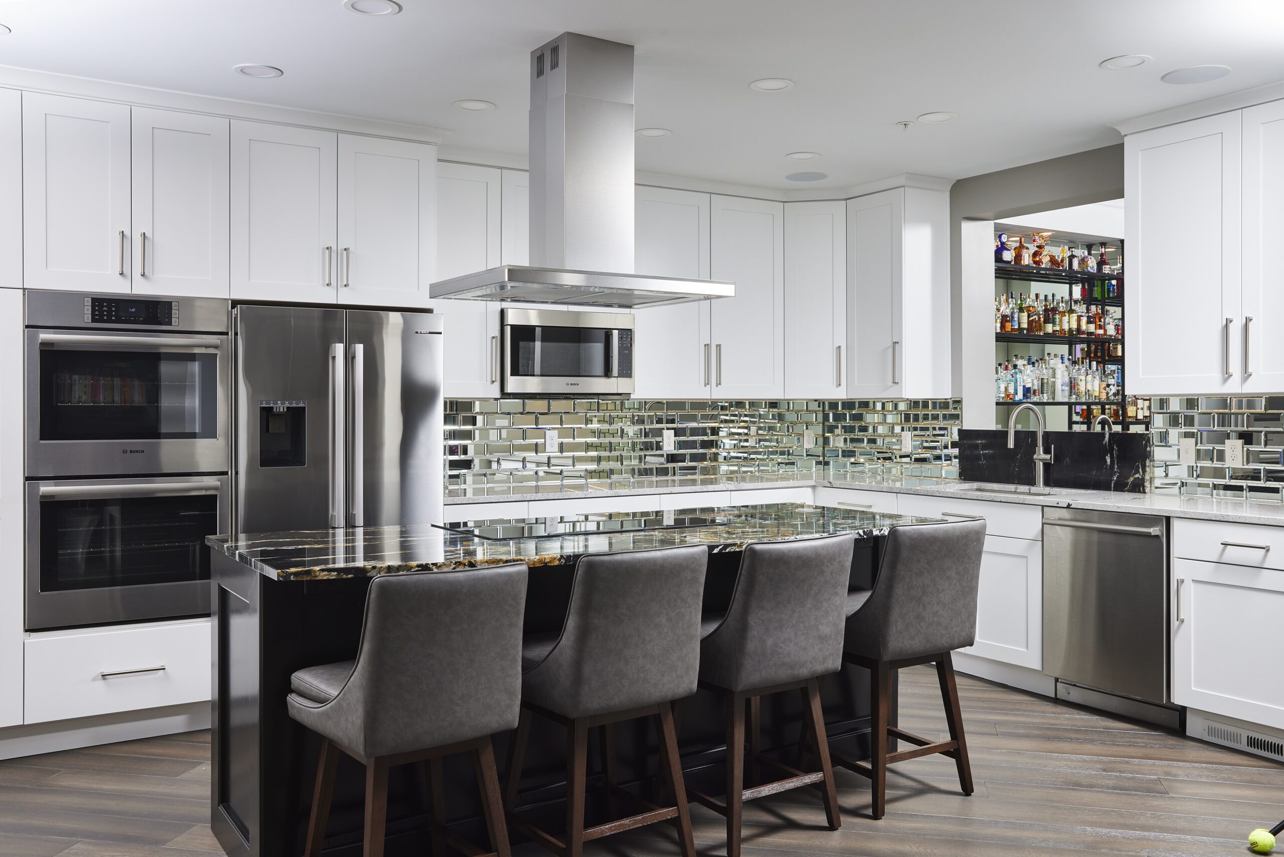 modern kitchen design with chrome, mirror and reflective surfaces. Long island with cooktop and stools for seating in photo.